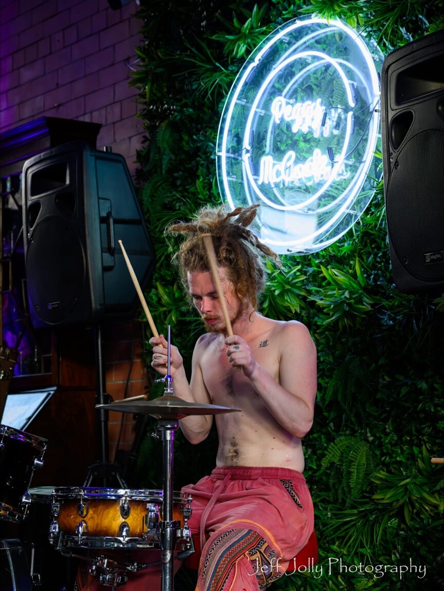 A drummer performing beneath the Peggy McCools sign