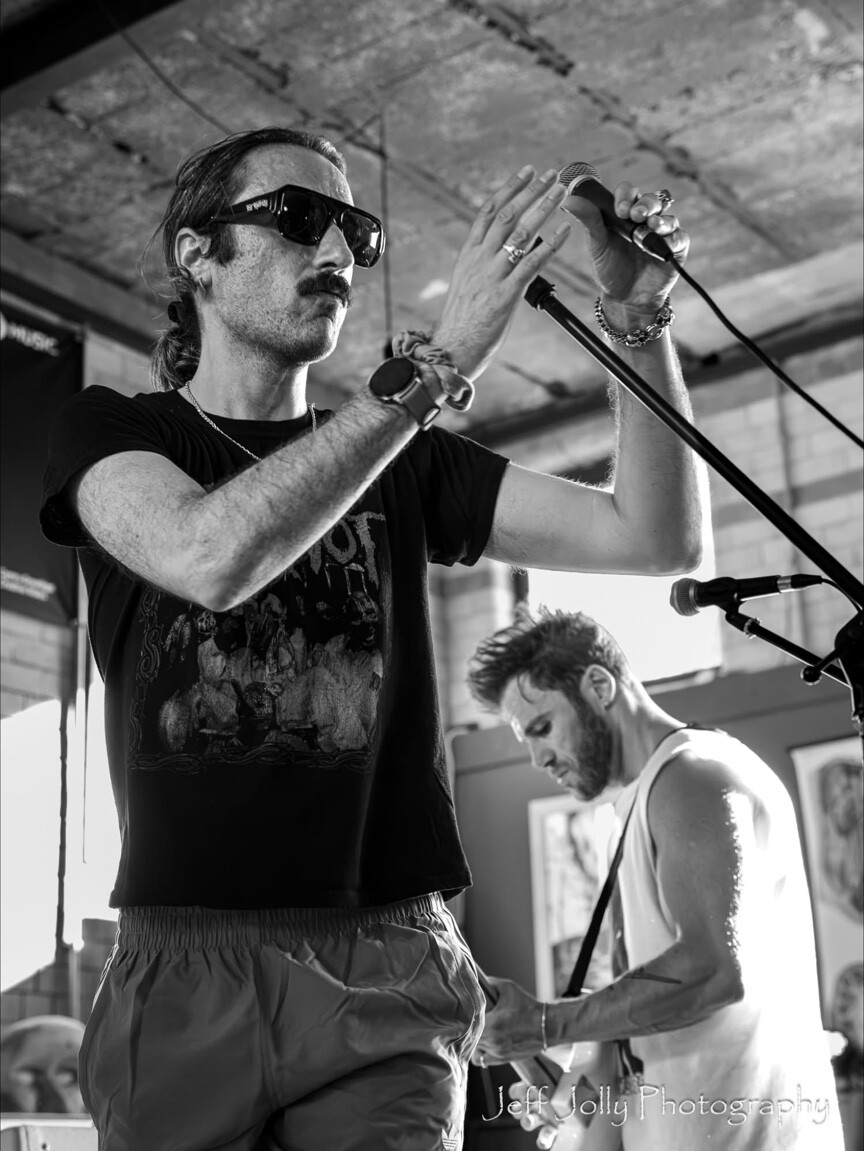 A singer adjusting a microphone in black and white