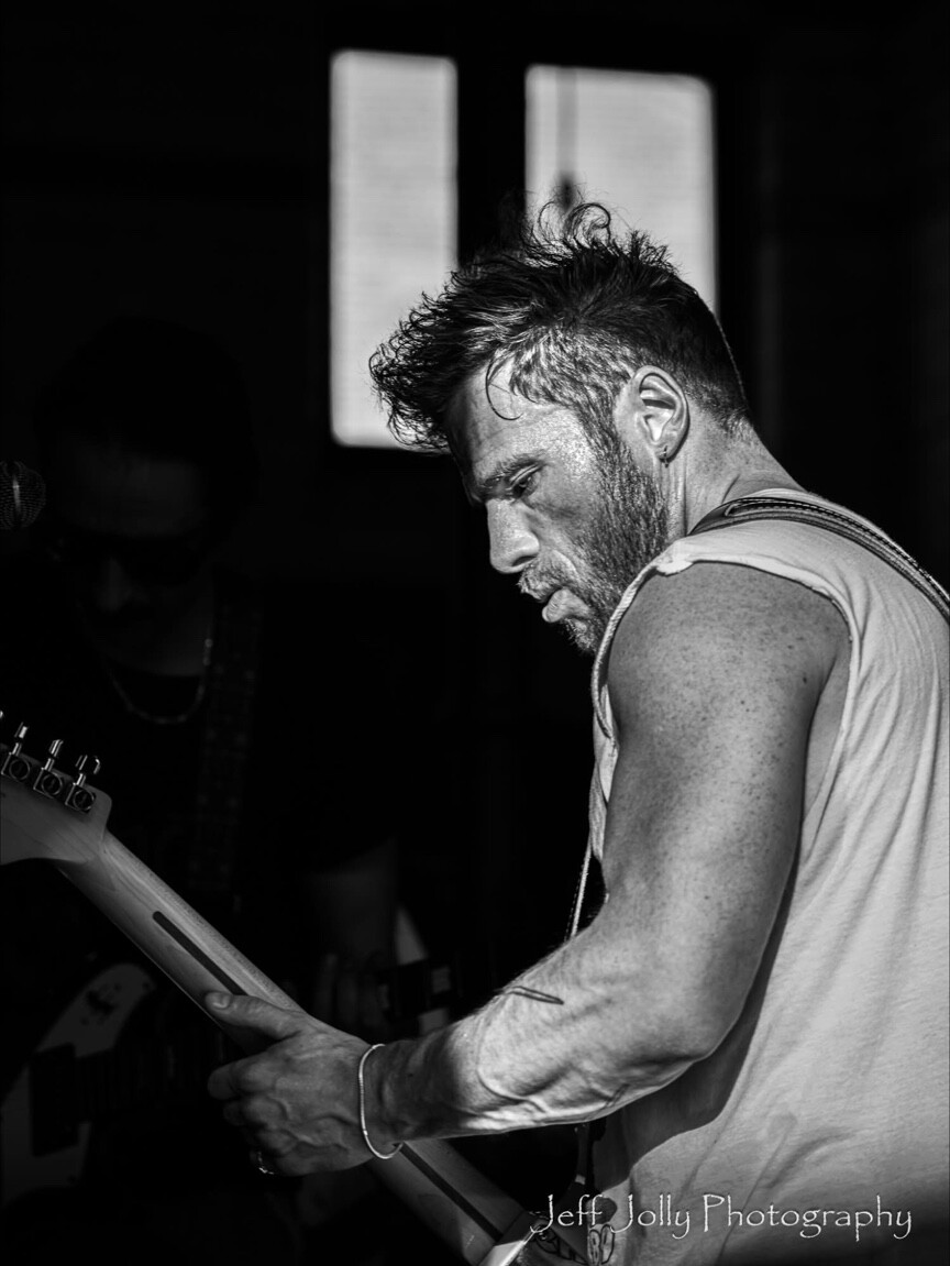 A guitarist performing in a black-and-white portrait