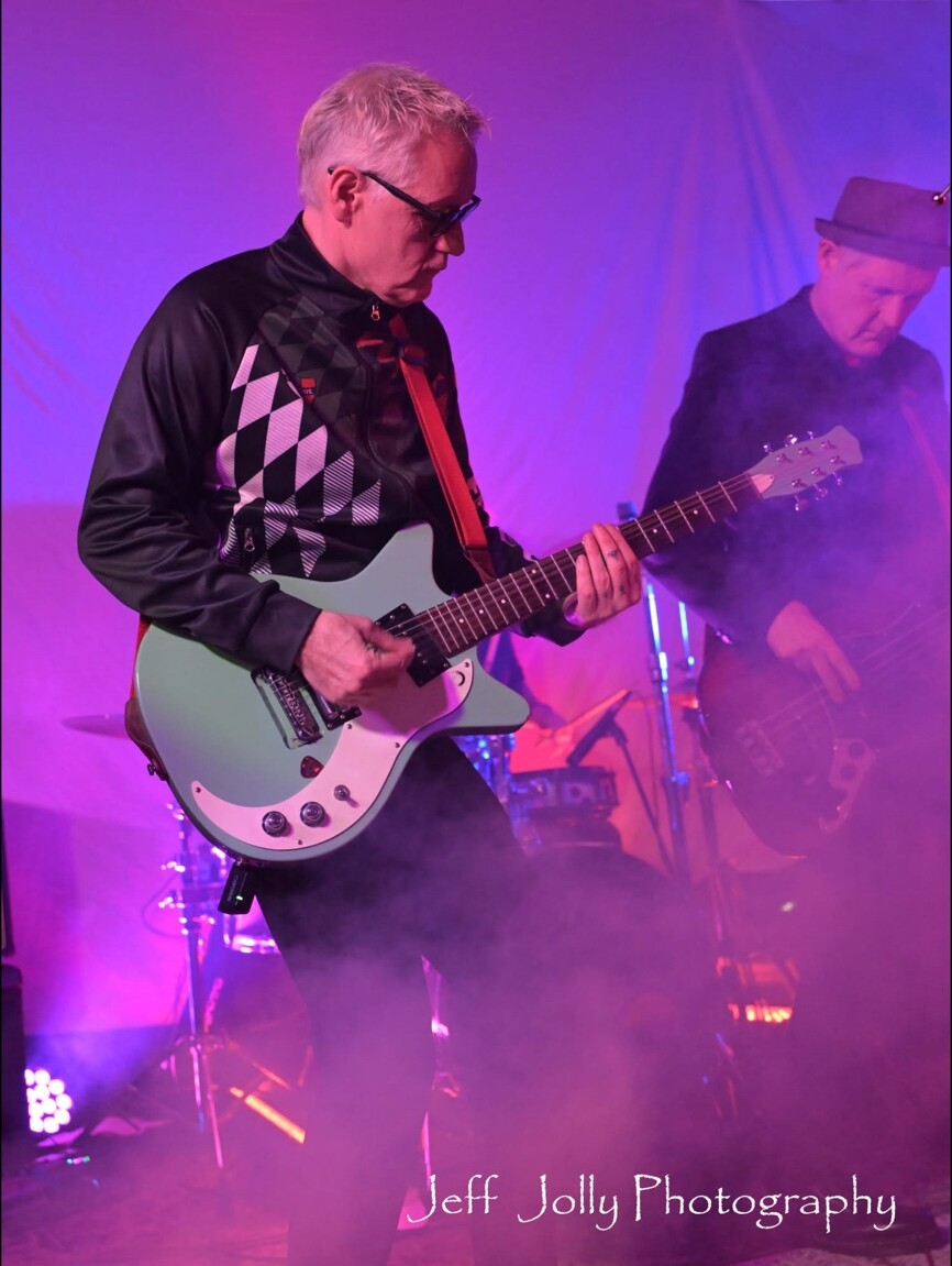 A guitarist playing through purple stage fog