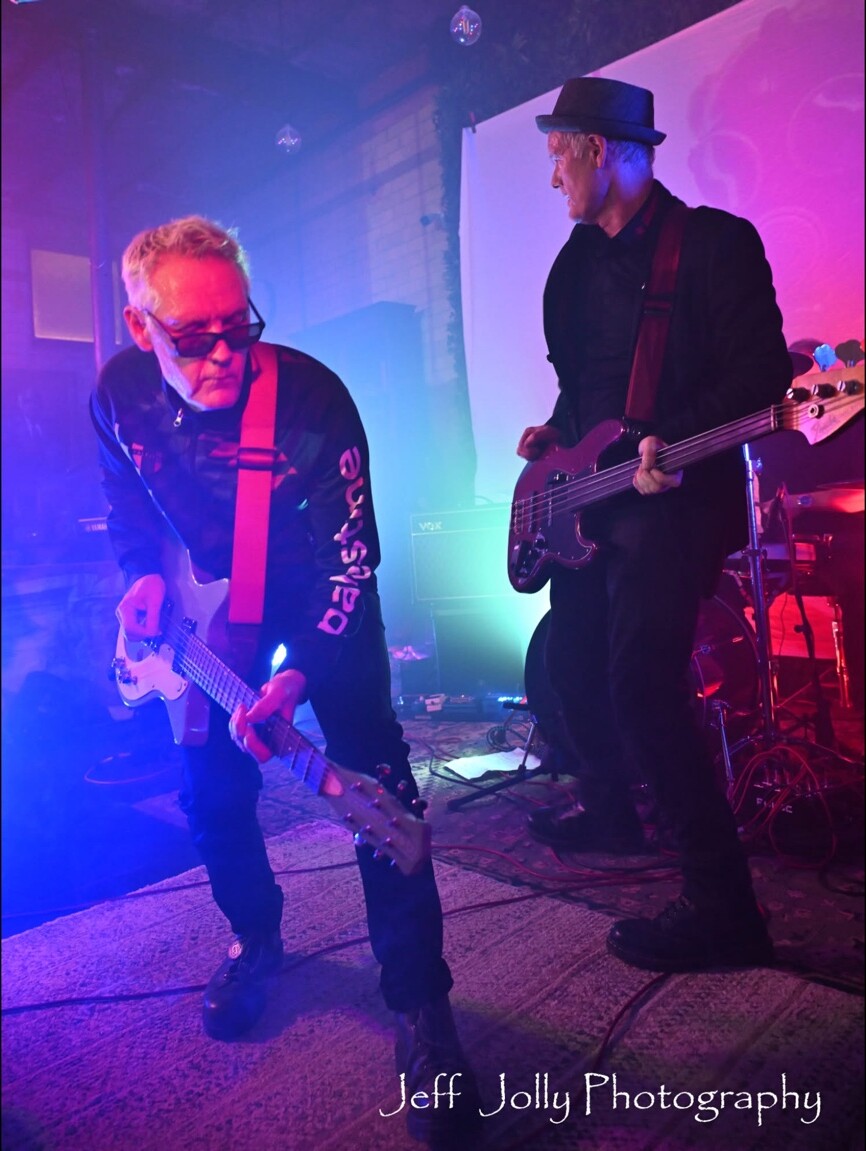 Two musicians playing together through purple stage fog