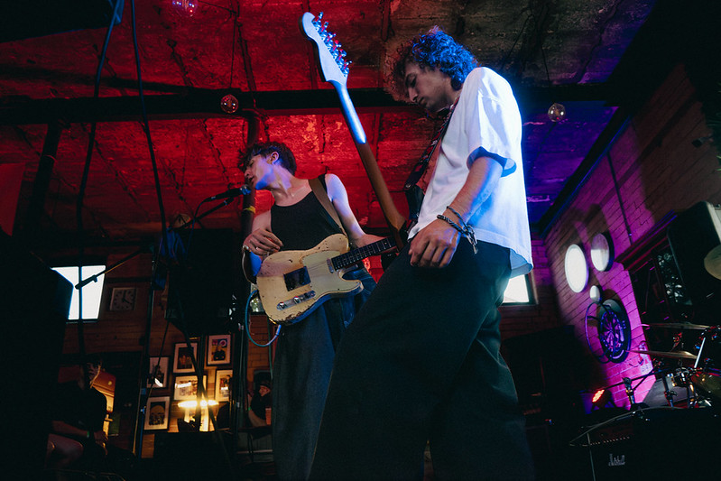 Two guitarists performing under red and blue stage lights